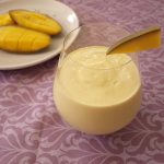 stemless wine glass with mango lassi inside and slice of mango as garnish