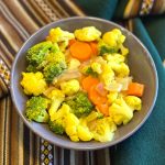 A bowl of broccoli, cauliflower, and chopped carrots in a yellow curry sauce.