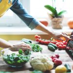 Person at a counter with veggies a tablet