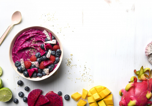 white bowl with a bright pink smoothie topped with berries