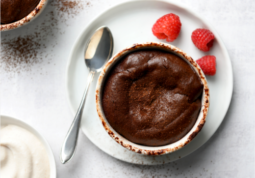 Molten Chocolate Cake in a ramekin with cocoa powder and raspberries