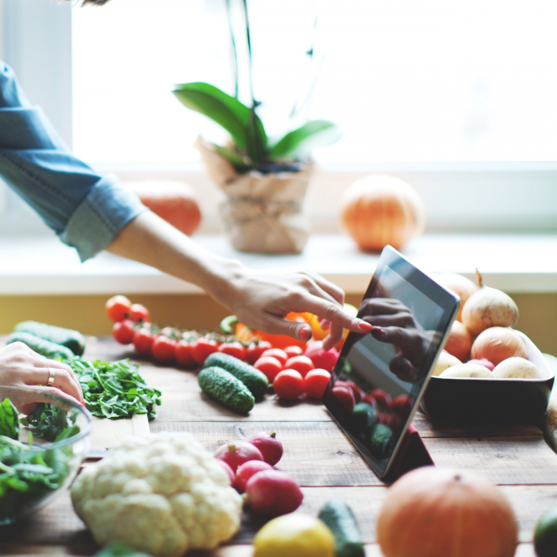 Person touching a tablet with veggies around