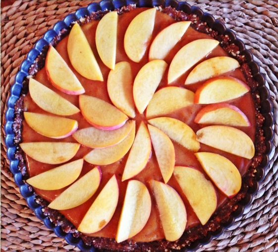 Sliced peaches on top of the Raw Peach Tart in a blue pie pan